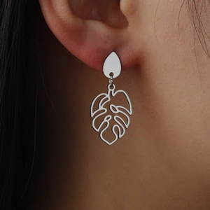 Silver hollow monstera leaf earrings in stainless steel on a female model