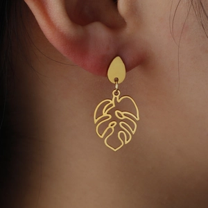 Golden hollow monstera leaf earrings with teardrop stud shown on a female model's ear