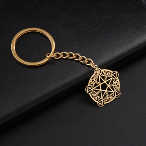 Detail of a hollow star geometric keychain with gold finish on black leather surface