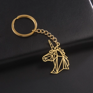 Polished gold geometric unicorn stainless steel keychain on black leather background