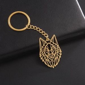 Modern geometric wolf head keychain in gold finish on a black leather background
