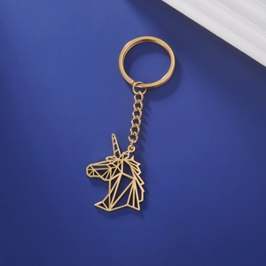 Detailed view of golden geometric unicorn keychain with metallic ring on blue background