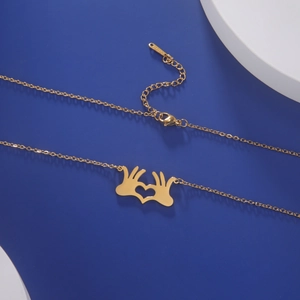 Dettaglio della collana con pendente mani a cuore in acciaio dorato su blu
