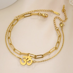 Detailed close-up of golden double-layer chain bracelet featuring an Om symbol pendant