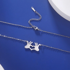 Dettaglio macro del ciondolo a gesto di mano a cuore d'argento e catena in acciaio inox