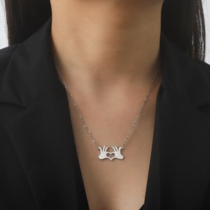 Collana con pendente mani a cuore argento indossata su elegante sfondo nero