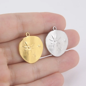 Handheld view of 18K gold and silver irregular star engraved stainless steel pendants
