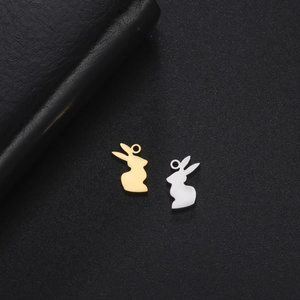 Vue macro de breloques lapin dorées et argentées sur fond noir pour bijoux DIY