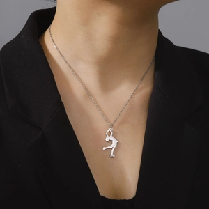 Silver ice skater silhouette pendant necklace worn over a professional black blazer