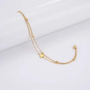 Detailed view of double-layer stainless steel bracelet with clover charm and gold beads
