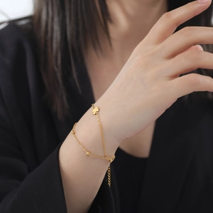 Elegant gold double-layer stainless steel bracelet featuring clover pendant and beads