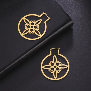 Detailopname van gouden holle oorbellen met symmetrisch patroon op zwart leeroppervlak