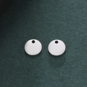 Macro shot of two round polished stainless steel pendant charms with small holes