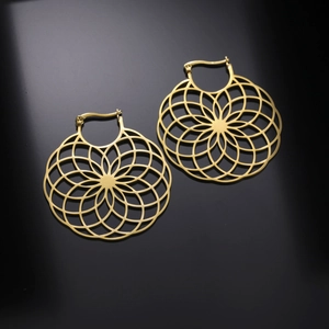 Macro shot of large golden flower earrings with complex geometric pattern and metallic finish