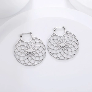 Macro detail of large hollow daisy pattern stainless steel hoop earrings in silver