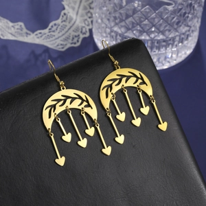Detail of gold crescent moon earrings with leaf filigree and dangling heart tassels