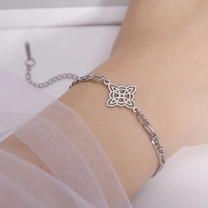 Detail of silver Figaro chain bracelet with Celtic knot pendant on woman's wrist