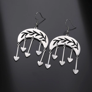 Detail of silver crescent moon earrings with hollow leaf patterns and heart dangles