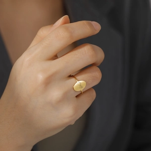 Minimalist gold oval ring with pinky swear engraving worn on a finger for a stylish look
