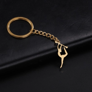 Détail d'un porte-clés doré en forme de silhouette de gymnastique sur fond noir texturé