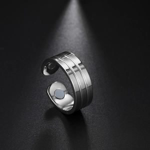 Polished silver magnetic therapy stainless steel open ring shown on a textured black background