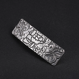 Detail of vintage silver hair clip with embossed peony flower and scrollwork pattern