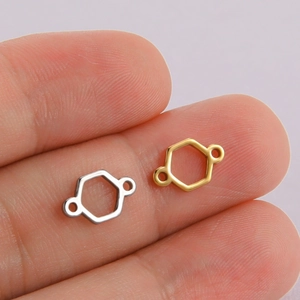 Gold and silver hollow hexagonal pendants on fingertips showing tiny jewelry part size