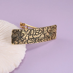 Detailed close-up of a vintage golden alloy hair clip with peony floral relief pattern