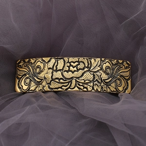Macro view of vintage bronze hair clip featuring intricate peony flower relief carvings