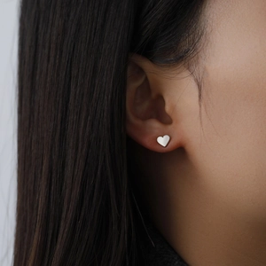 Minimalist heart-shaped stainless steel stud earrings shown on model for a natural look
