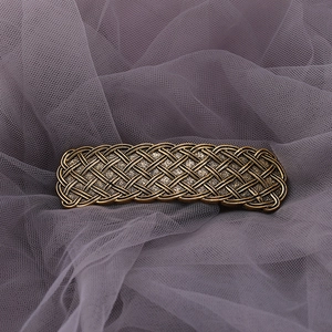 Macro detail of vintage bronze Celtic barrette with intricate metallic woven texture