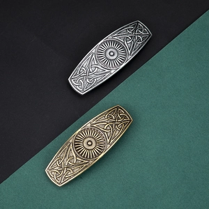 Close-up of vintage Celtic knot hair clips with sun patterns in antique bronze and silver
