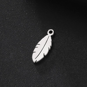 Macro shot of silver stainless steel feather pendant with polished metal texture