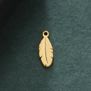 Elegant gold feather pendant in polished stainless steel on a dark green background