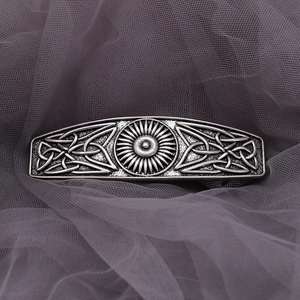 Detailed close-up of retro silver Celtic knot hair clip on a purple mesh background