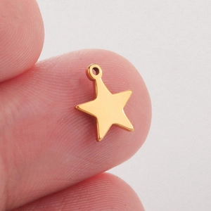 Macro-opname van een gepolijste gouden ster hanger in de hand voor DIY-sieraden