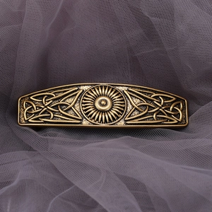 Macro detail of vintage Celtic knot hair clip in bronze finish on purple mesh fabric