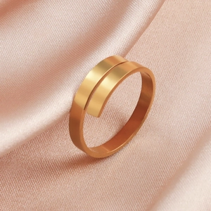 Nahaufnahme des goldenen verstellbaren Spiralrings auf elegantem rosa Seidenstoff