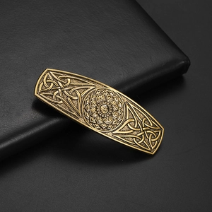 Détail d'une pince à cheveux vintage en métal avec nœuds celtiques et motif lotus Om