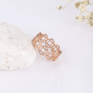 Macro detail of rose gold hollow coin ring on white stone background with soft shadows
