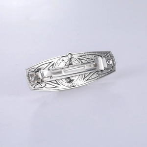 Close-up of vintage silver hair clip showing Celtic patterns and spring mechanism