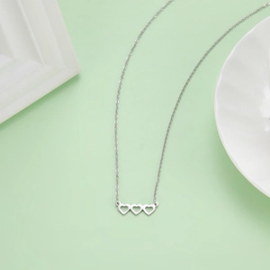 Collana minimalista in acciaio inox argento con tre cuori vuoti su base verde chiaro