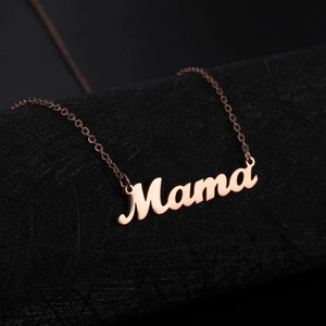 Close-up of rose gold Mama pendant on fine chain over a dark textured cylinder
