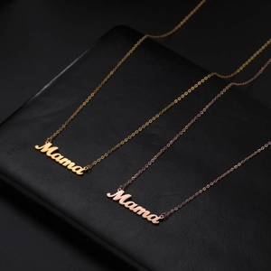 Modern 18K gold and rose gold Mama letter necklaces on textured leather background