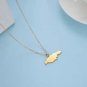 Detailopname van een gouden Jamaica-kaart hanger aan een fijne roestvrijstalen ketting