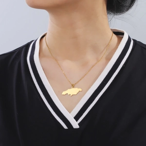 Gepolijste gouden Jamaica kaart hanger ketting gedragen door model aan een fijne schakelketting