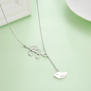 Detail of silver stainless steel leaf and bird pendant necklace on pale green background