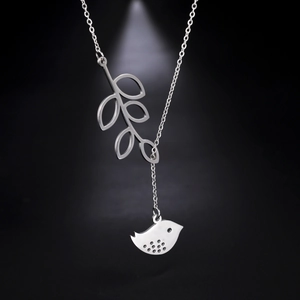 Minimalist stainless steel leaf and bird pendant necklace on a sleek black background