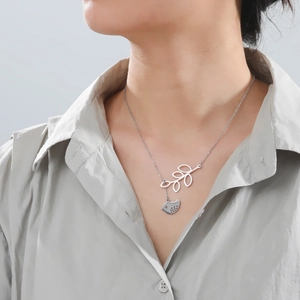 Minimalist stainless steel necklace featuring hollow leaf and solid bird pendant on a model