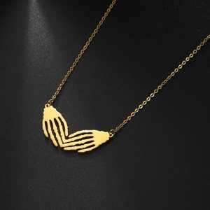 Macro shot of punk skeleton hands forming a heart pendant on a gold gothic necklace